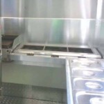 Interior view of a customizable food truck with gas stoves, fryers, and stainless steel countertops